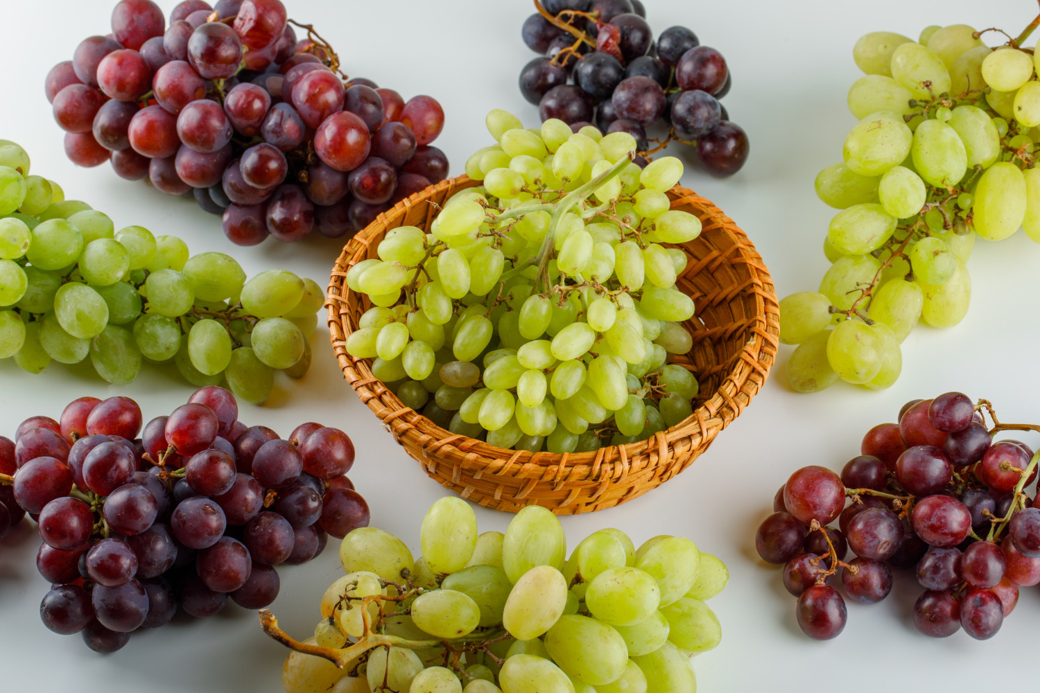 Ripe grapes in a wicker basket high angle view on a white Grapes and raisins are toxic to dogs and toxic and can cause sudden acute kidney failure