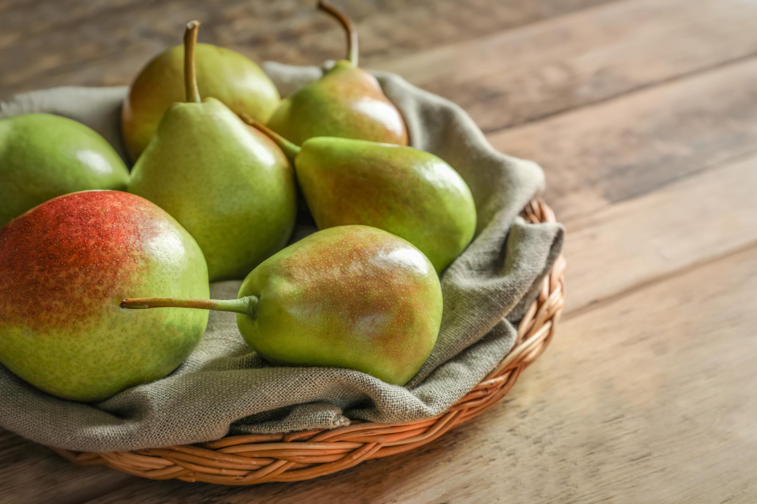 Wicker plate with delicious ripe pears on table Pears, without their seeds or core, are relatively healthy for dogs and provide valuable vitamins, minerals and fiber.